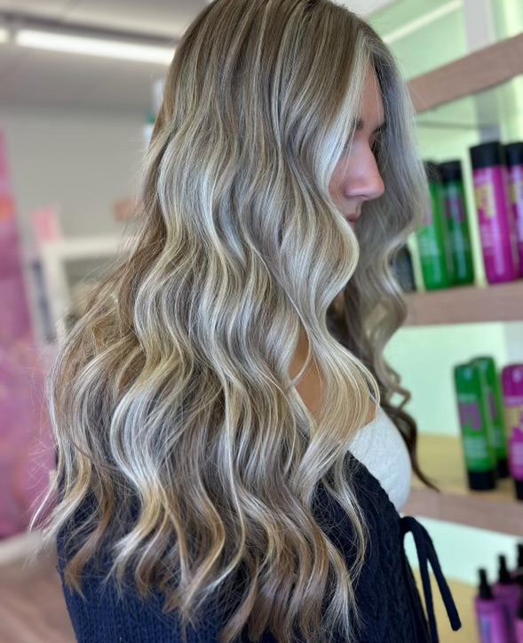 Blonde woman with long wavy hair. Dimensional balayage with blonde money piece
