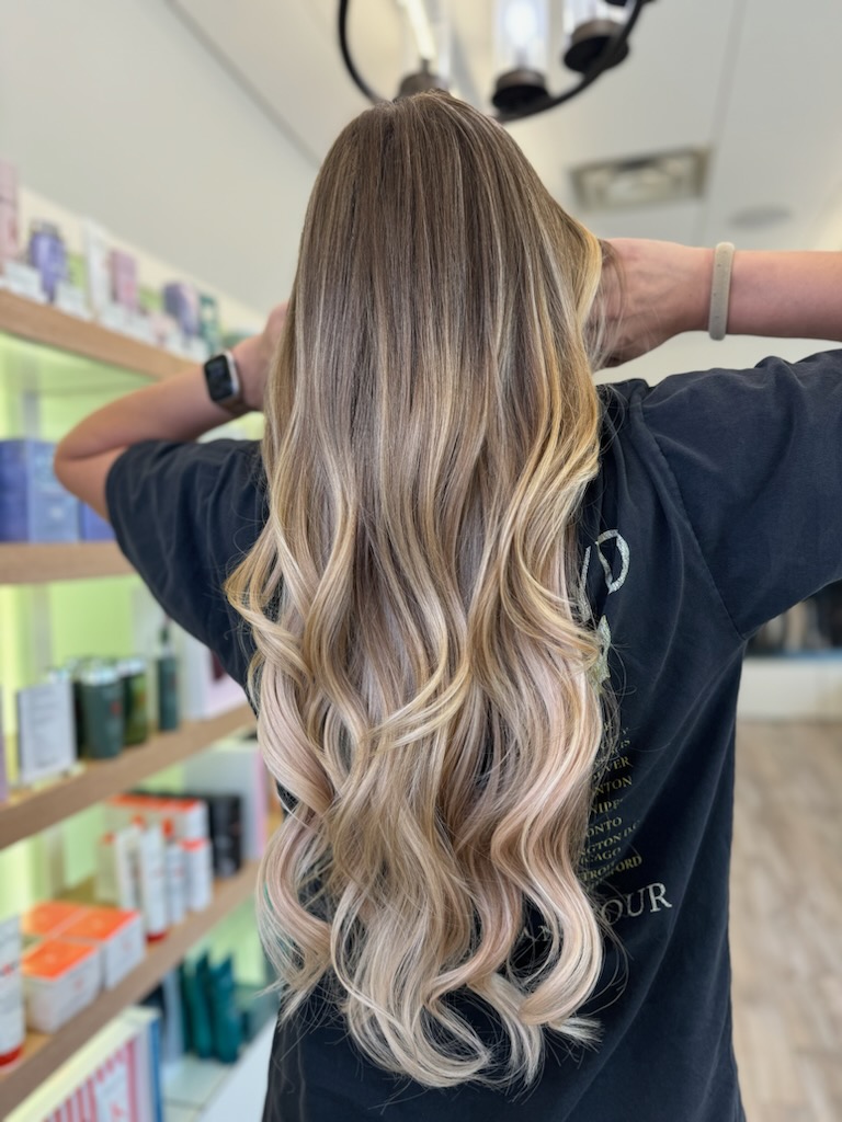 Long blonde hair shown from the rear. Low-maintenance blonde balayage.