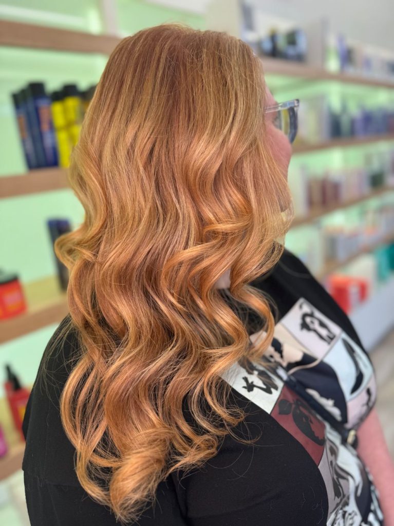 Long reddish hair shown from the rear. Copper blonde balayage