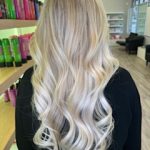 A blonde woman showing her hair from behind with Bombshell Luxe Extensions installed.