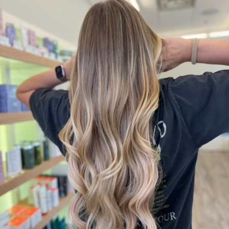 Long blonde hair with extensions shown from the rear. Low-maintenance blonde balayage.