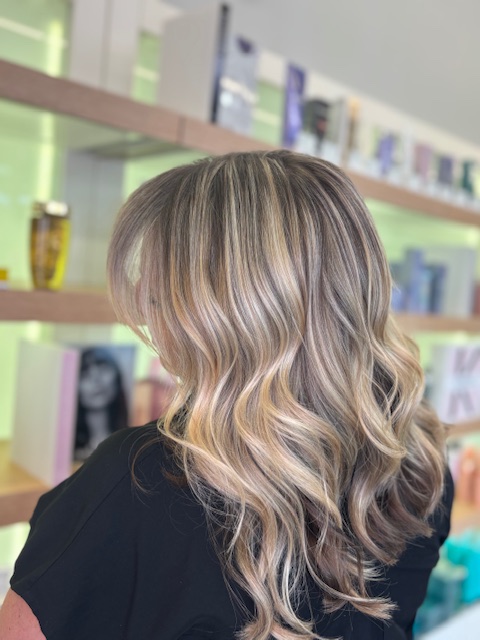 Blonde woman with long hair after receiving a color treatment.