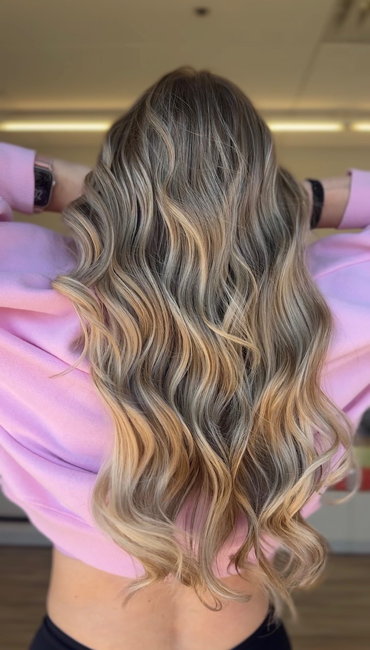 balayage-lived-in color Blonde woman from the rear view showing long wavy hair and balayage-lived-in color
